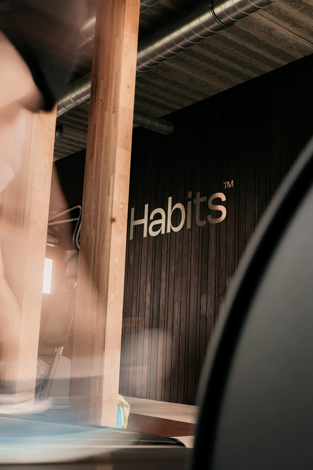 Het Habits-logo op de warme houten wand in de club