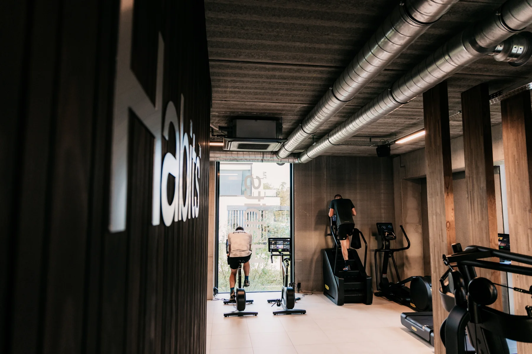 De cardiozone van Habits Kortrijk met fietsen en een trappenloper aan het raam