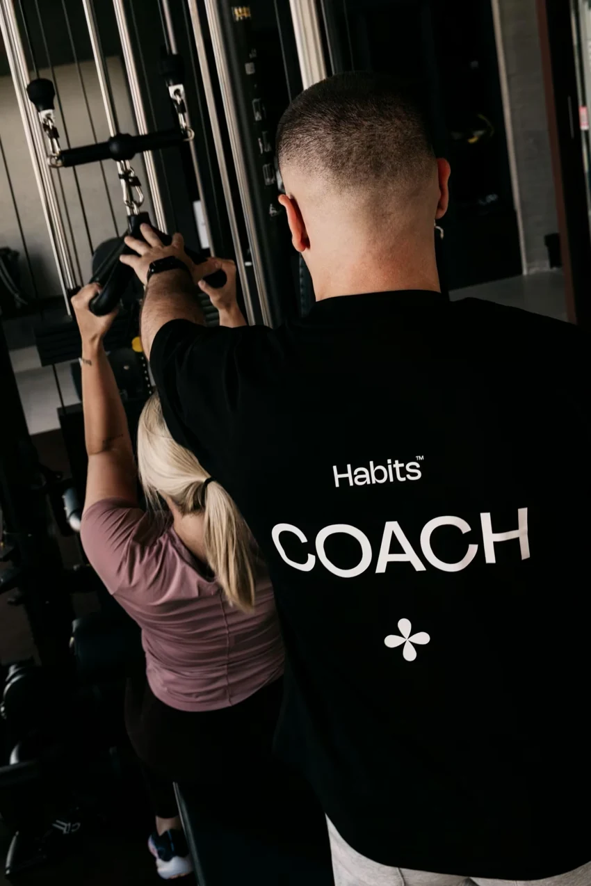 Een coach van Habits begeleidt de uitvoering van een lid aan het kabelstation