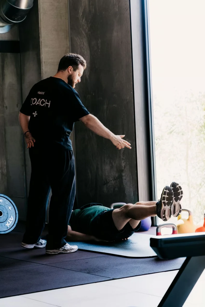 Een coach van Habits begeleidt een lid tijdens een oefening op de mat