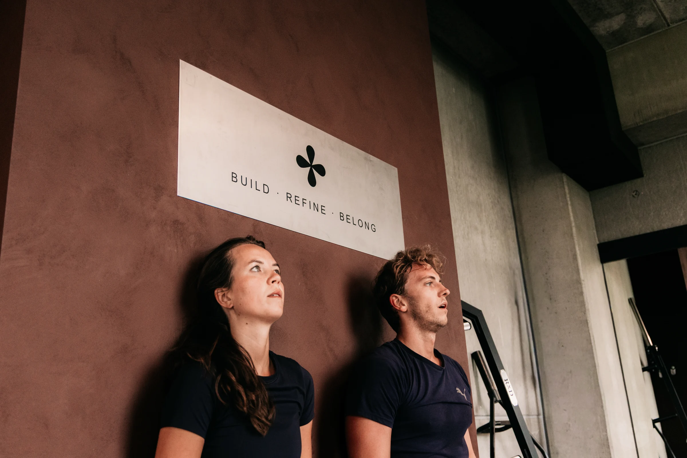 Twee leden bij de terracotta Habits-wand tijdens hun training