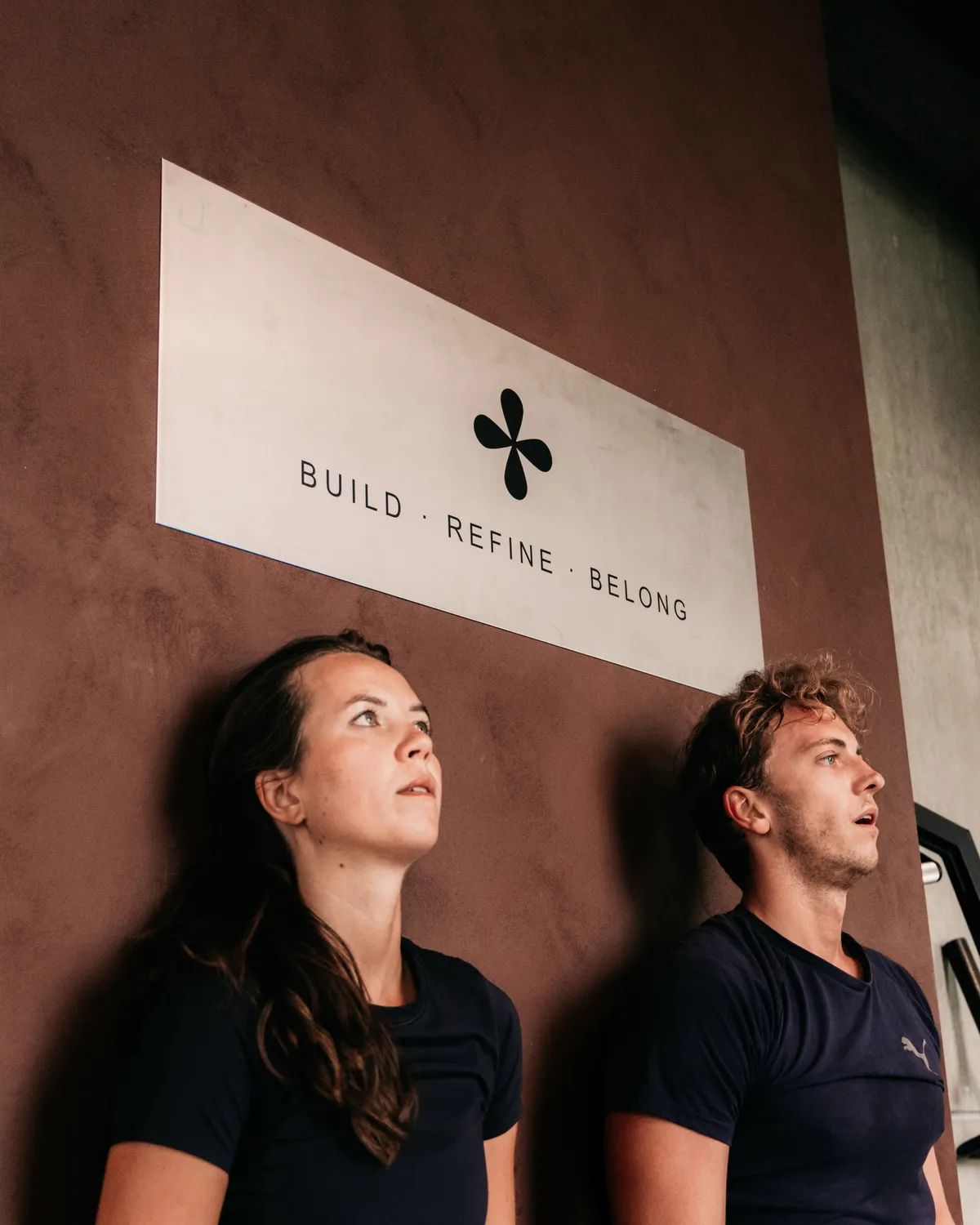Twee leden van Habits samen na hun training, onder het bord Build, Refine, Belong