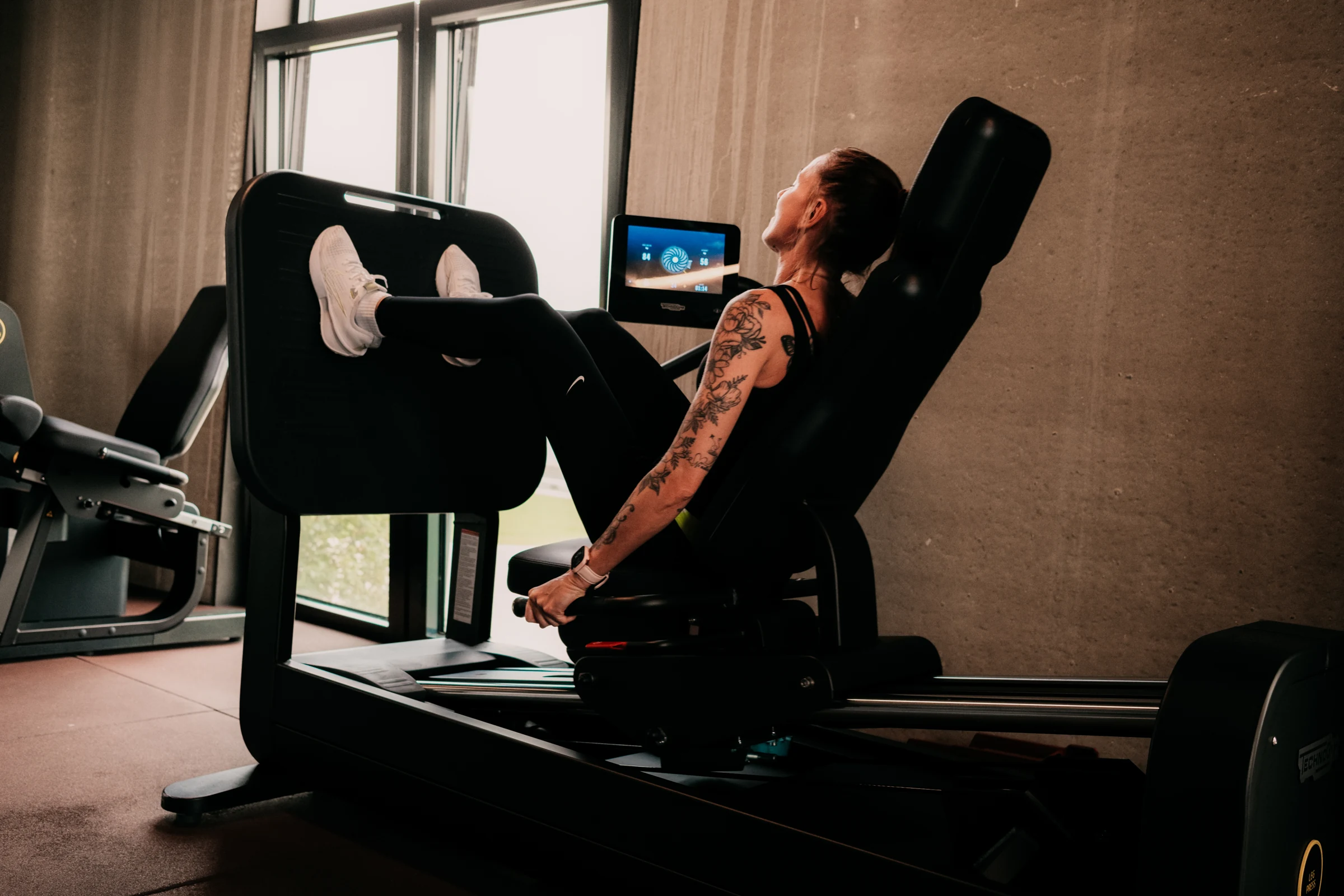 Een lid traint op de Biostrength-legpress van Technogym, met het scherm naast zich