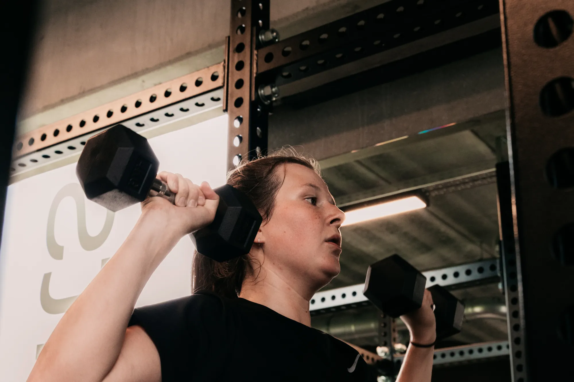 Een lid traint met dumbbells aan het rek bij Habits