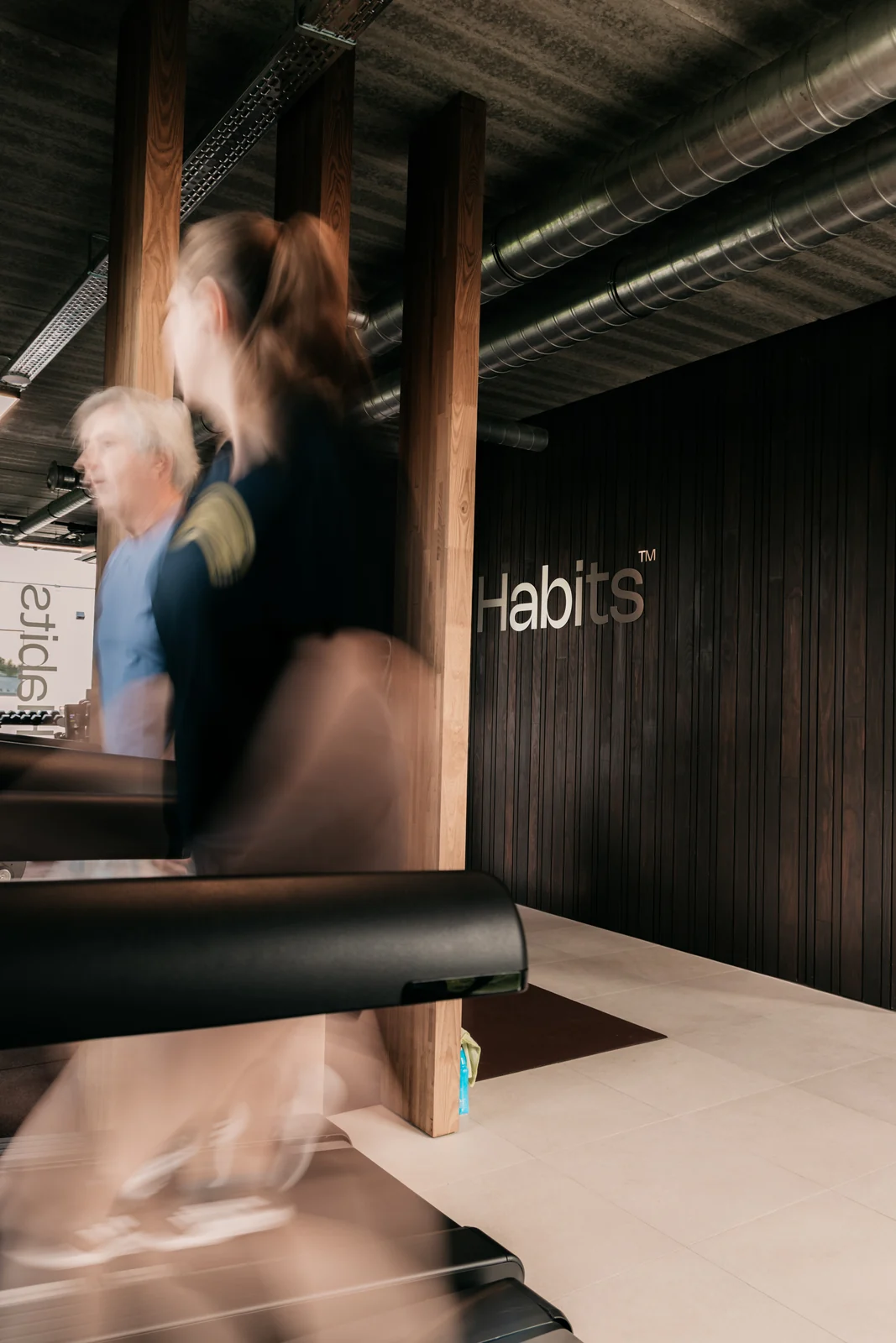 Een lid beweegt tussen de houten kolommen van Habits