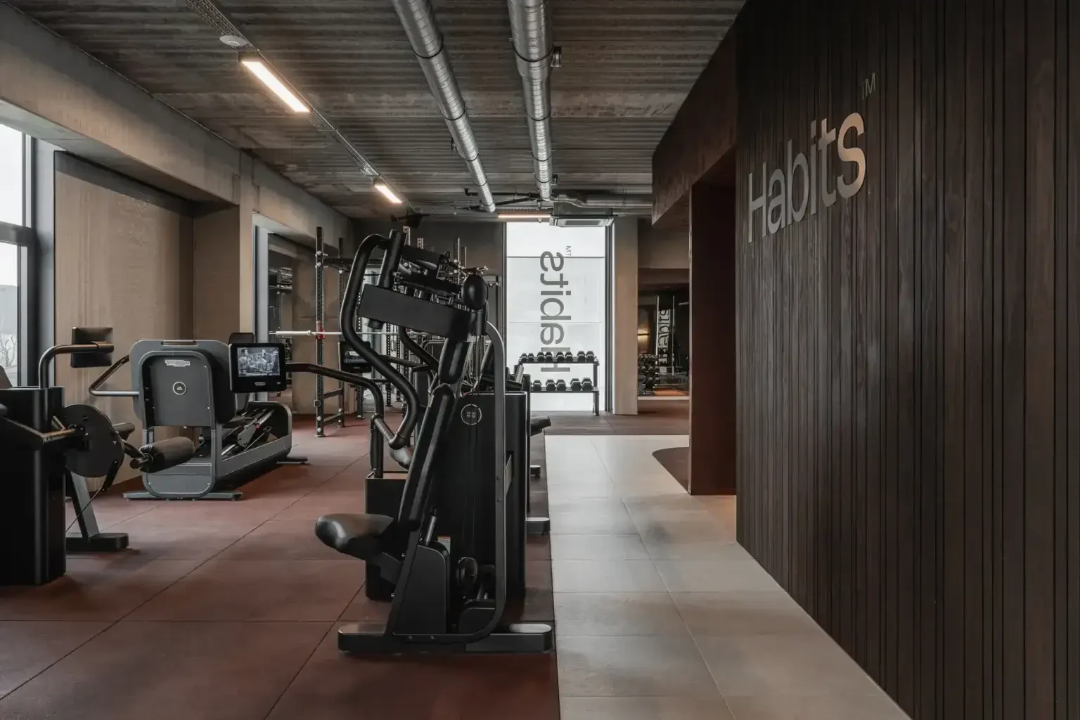 Habits Kortrijk met Technogym-toestellen en de houten wand met het Habits-woordmerk