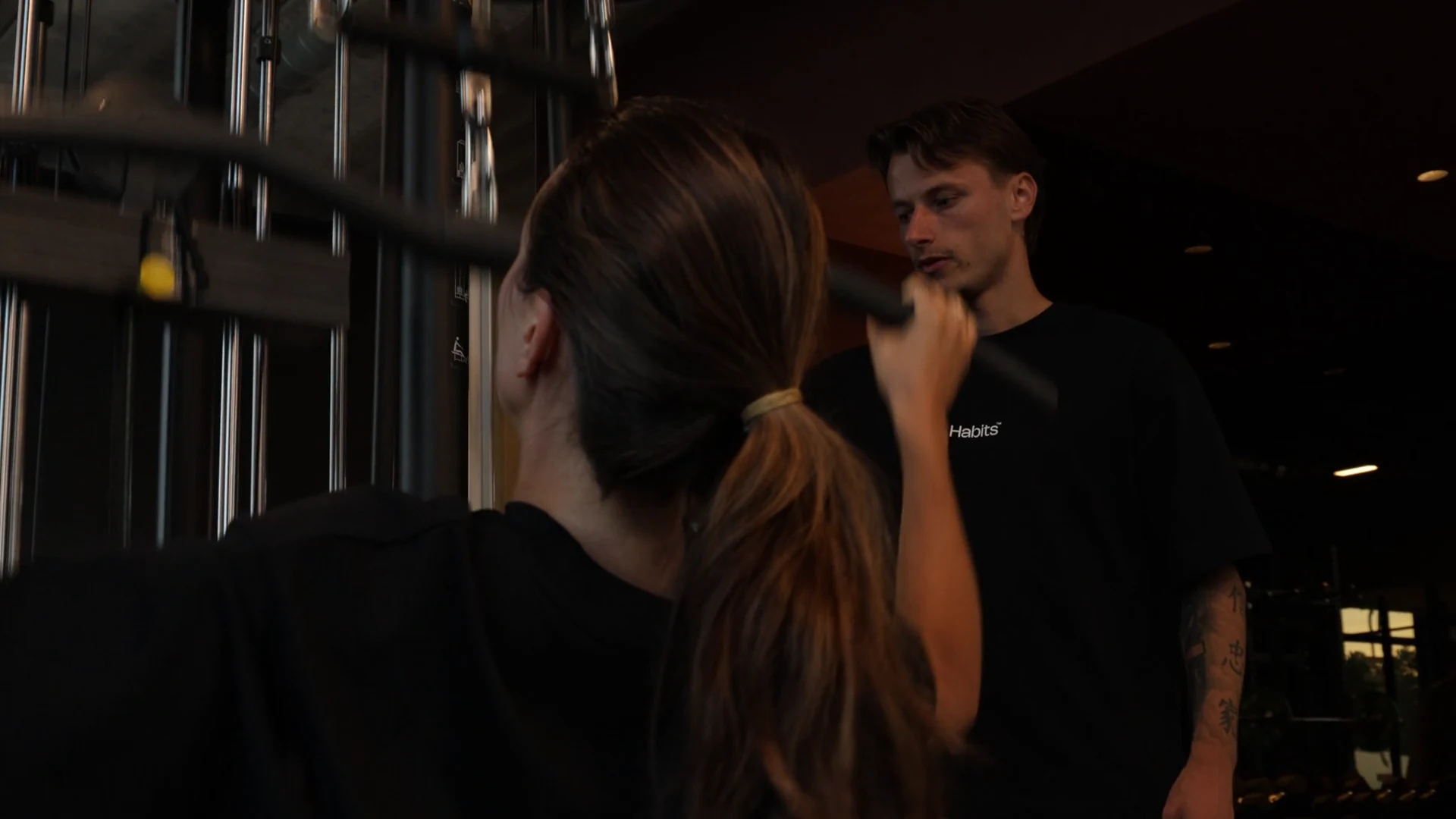 Een coach begeleidt een lid bij een kabeloefening bij Habits