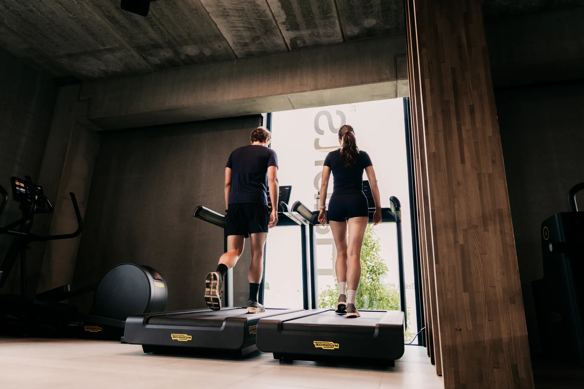 Twee leden op de Technogym-loopbanden aan het raam bij Habits